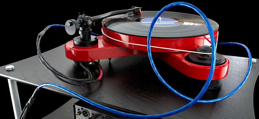 Blue Heaven tonearm cable connected to a red turntable on a black wood audio rack