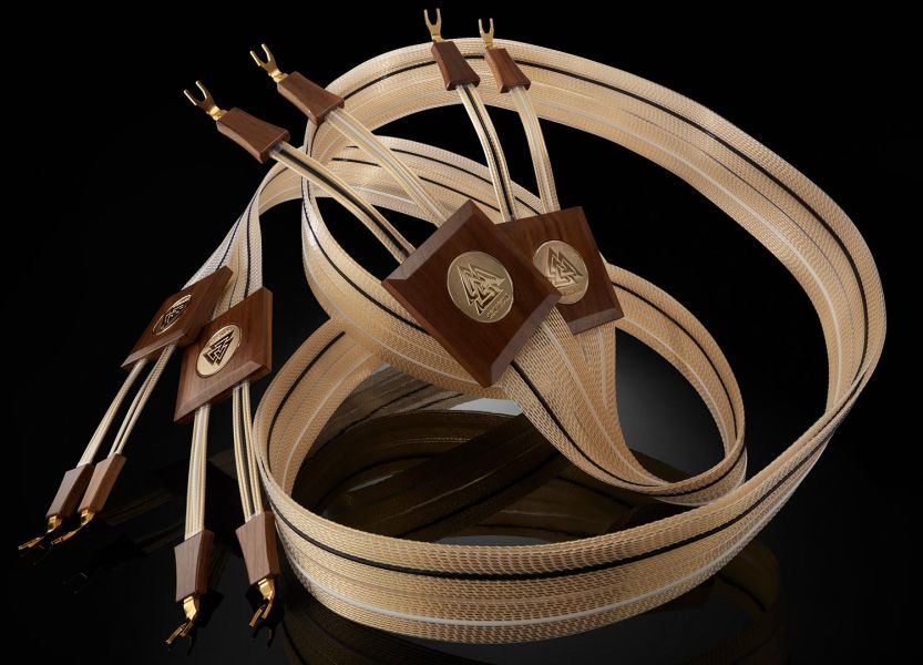 Luxurious flat Nordost speaker cables with gold and wood accents coiled elegantly on black surface
