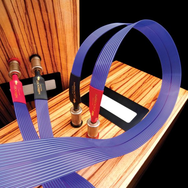Purple Nordost speaker cables connected to wood-finished speakers with banana plugs